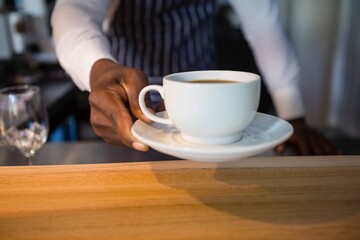 Mid section of waiter giving coffee at cafe