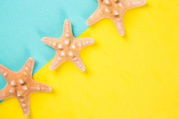 Three starfishes on colored mint and yellow backgrounds with negative space, top view