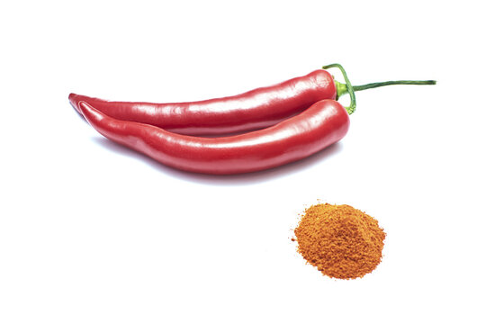 Red chili peppers next to the pepper powder pile on the white background