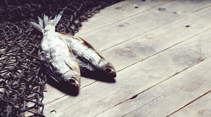 Sun dried fish and fishing nets on the wooden background.