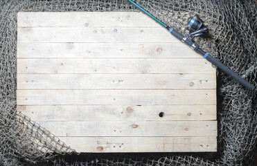 Fishing nets and spinning rod over the wooden background. Still-life and objects.