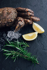 Crab on a dark stone with lemon and ice cubes