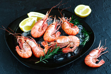 Tiger shrimps with lemon, rosemary on stone background.