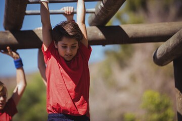 Obraz premium Kids climbing horizontal bars during obstacle course training