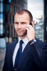 businessman talking on his cellphone while walking outdoors