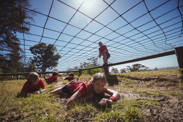 Kids crawling under the net during obstacle course training