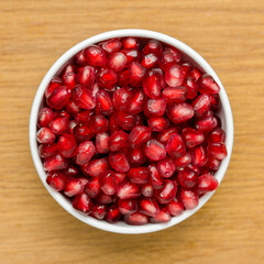 Grains Of Pomegranate In A White Bowl On A Wooden Board. Close-Up. Free Space For Text. Top View.