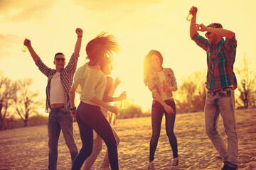 Happy young people having fun on the beach and drinking beer