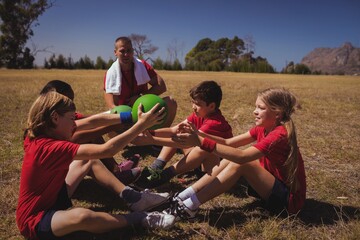 Trainer instructing kids while exercising in the boot camp