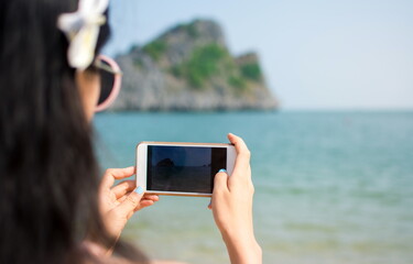 Girl taking a picture with phone on the beach