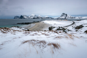 A road through the winter landscape leads to the houses of fishermen. Myrland Lofoten Islands Northern Norway Europe