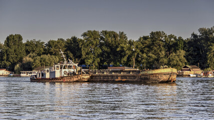 Fototapeta na wymiar A tugboat pushes barge along the river