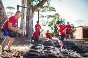 Trainer instructing kids during tires obstacle course training
