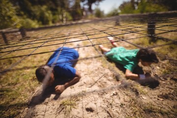 Kids crawling under the net during obstacle course