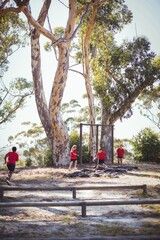 Fototapeta premium Group of kids running over tyres during obstacle course training