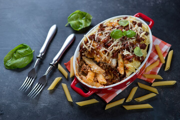 Baking dish with traditional italian ziti on a dark metal background, horizontal shot