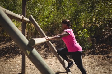 Fototapeta premium Woman exercising on outdoor equipment during obstacle course