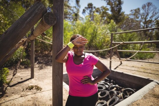 Tired woman wiping sweat after workout during obstacle course