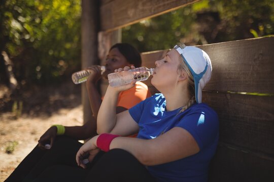 Friends drinking water after workout during obstacle course