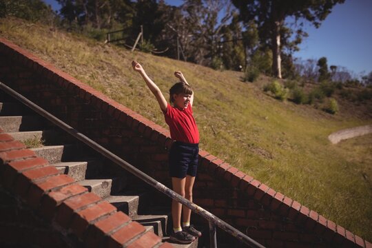 Happy girl cheering on staircase during obstacle course
