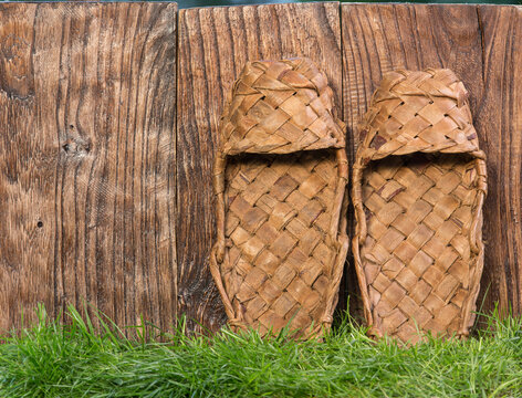Bast shoes, ancient peasant straw shoes, wooden, rustic wall