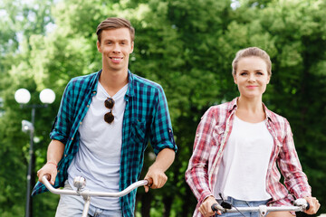 Happy traveling couple riding on bicycles. Boyfriend and girlfriend in old town. Love, relationship, romance concept.