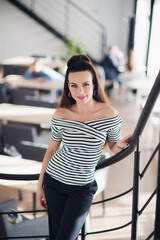 Portrait of young brunette woman posing for camera in a cafeteria while looking at the camera.
