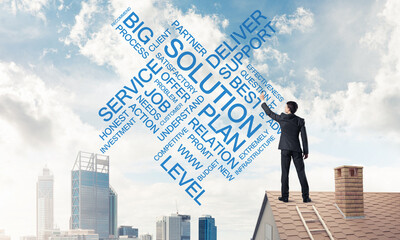 Young businessman standing on house roof and writing leadership 