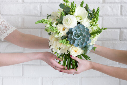 Delivery of bouquets from hand to hand. Business - making floristic compositions to order for customers. White roses and succulent in modern wedding assembling