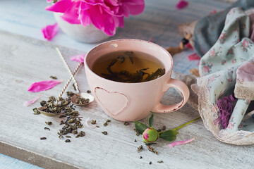 Still life with pink peony flowers and a cup of herbal or green