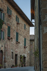 Fototapeta premium Montichiello - Italy, October 29, 2016: Quiet street in Montichiello, Tuscany with typical shuttered windows and paved streets. Monticchiello is the only fraction of the municipality of Pienza, in th