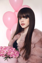 Fashion woman in fur coat, lady portrait over gift. Glamour brunette with rose bouquet of flowers in hat box over balloons isolated on white studio background.