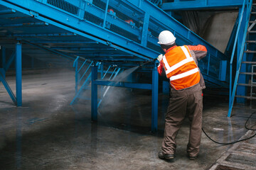 The worker washes the equipment at the waste sorting plant. Waste processing plant. Technological...