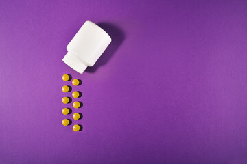 Medical pills on a colored background with a white vial