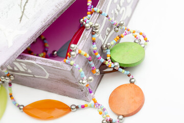 Wooden beads close-up is on the table. Multicolored necklace is in the casket.