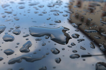 Water drops on a blue metal surface and buildings reflections