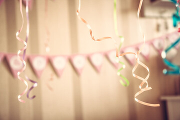 Vintage happy birthday party blurred background with hanging ribbons and garland in decorated room in pastel colors