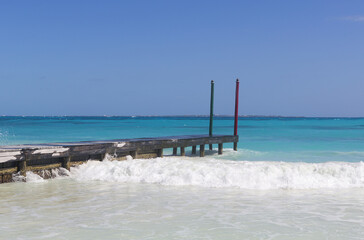 Wooden pier on the shores of the Caribbean ocean. Turquoise water with white sand beach. Vacation concept image. Copy space.