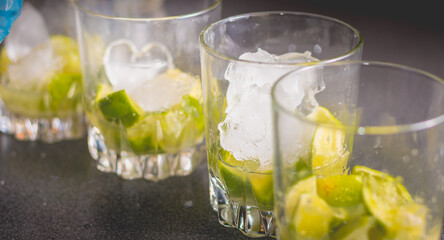 bartender puts ice cubes in glasses of brezillian caipirinha