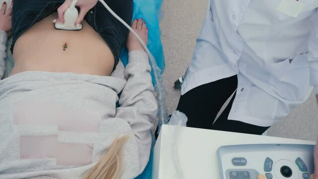 The girl makes an ultrasonography of stomach in clinic