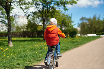 Naklejka premium Small boy ride bicycle in street park.