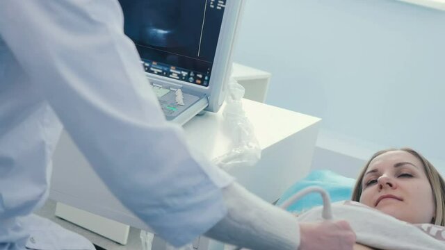 The doctor makes the ultrasonography of female's abdomen