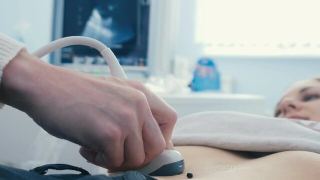The sensor of the sonograph touches the abdomen