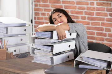 Businesswoman Sleeping On Folder Stacked In Office