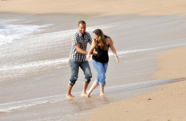 Young happy couple dating and teasing on the beach