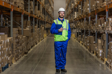 Warehouse worker standing between rows with merchandise and looking at camera