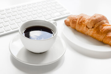 croissant and cup of coffee on office desk for business breakfast white background