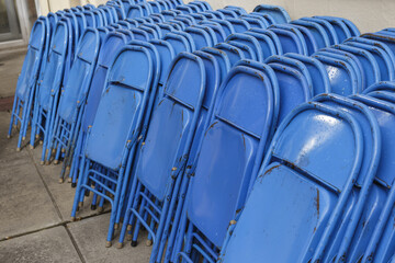 stacks of blue folding chairs up against the side of a building