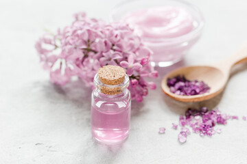 Obraz na płótnie Canvas lilac cosmetics with flowers and spa set on stone table background