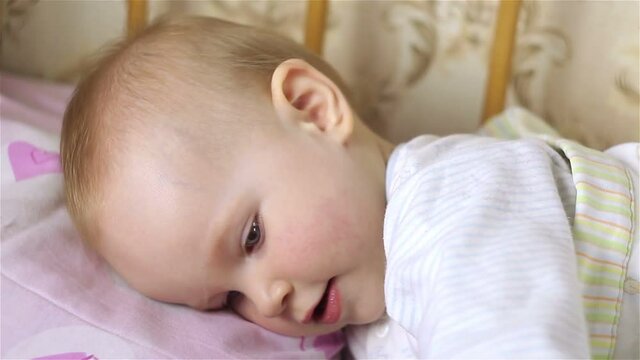 Little baby girl is lying in bed, smiling. close-up.